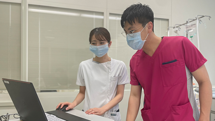 パソコンを確認している医療従事者二人の写真